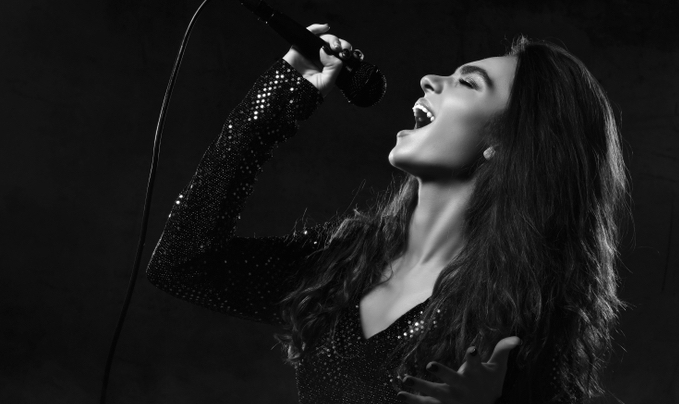 Beautiful woman singer sing with microphone on stage, dark background, smoke, spotlights