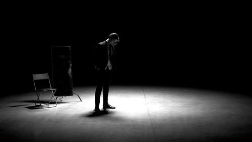 Man in suit alone playing on stage of theater. 