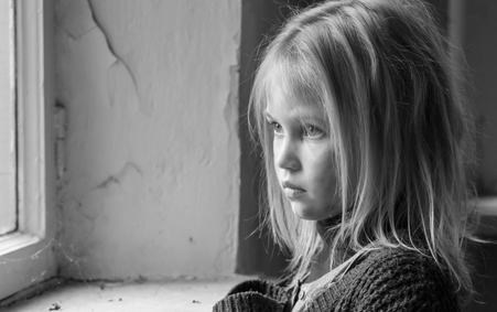 little girl, alone, looking through the window