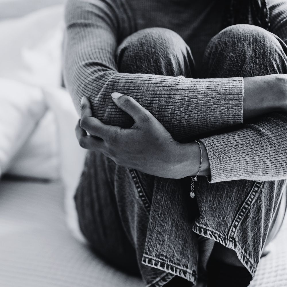Person hugging knees while sitting