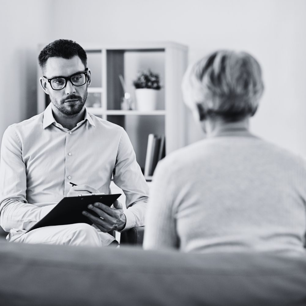A therapist listening intently while holding clipboard and pen