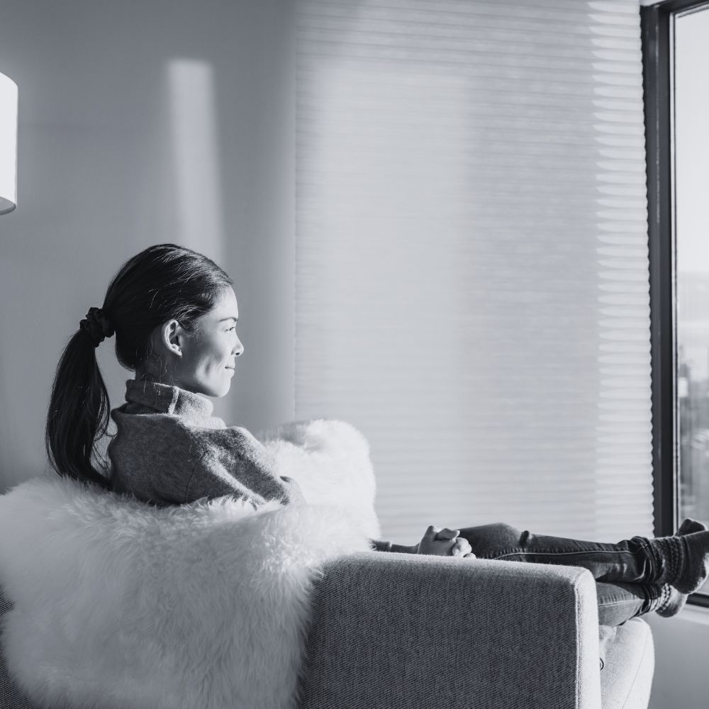 Young woman sitting peacefully on chair while looking out window