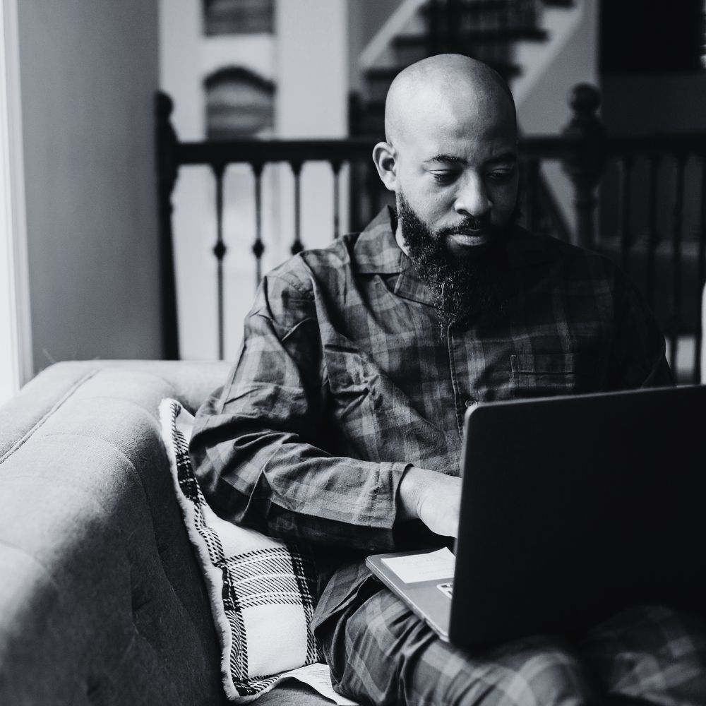 Man sitting on couch using laptop for online therapy session