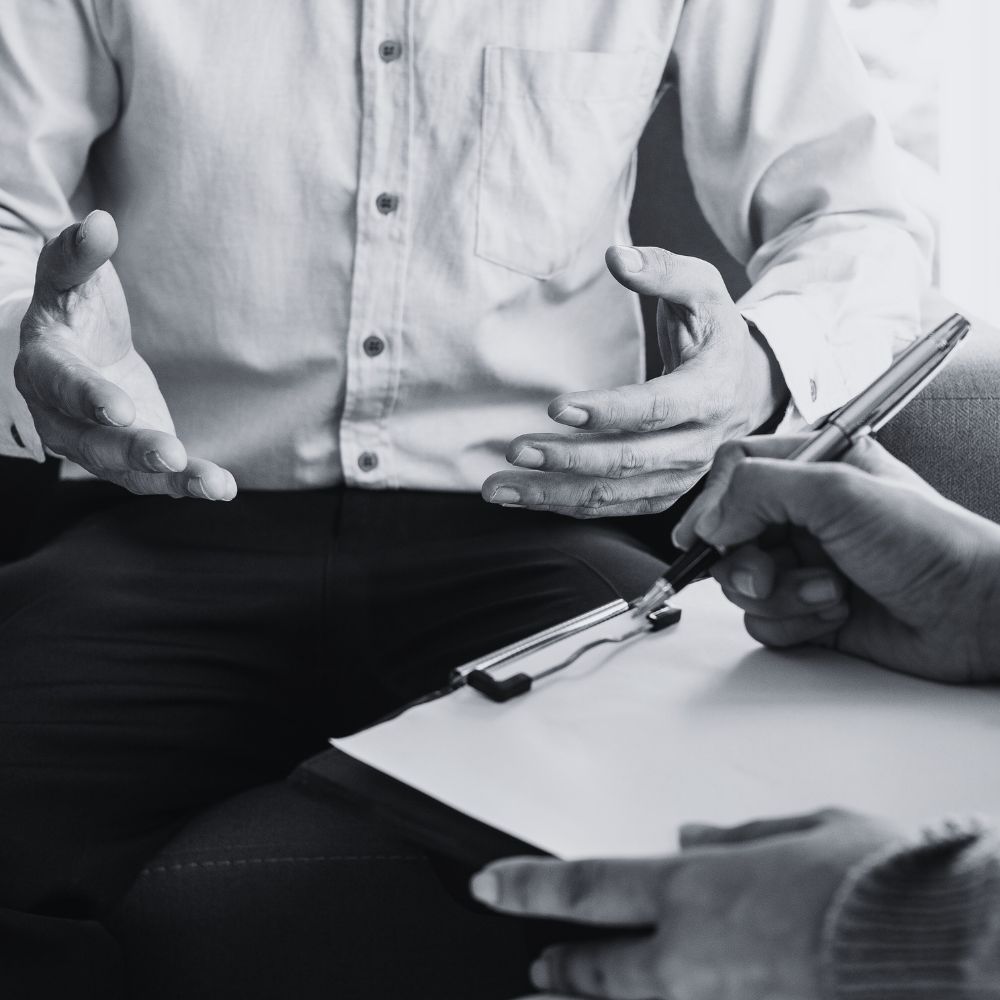Therapist taking notes while client gestures during a session