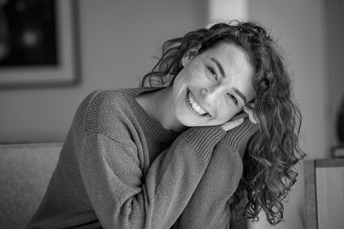 Happy woman sitting on sofa at home.