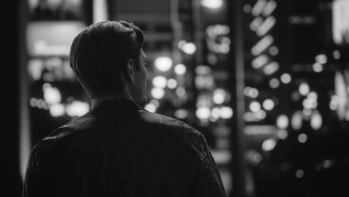 Man alone on the street, back image, looking for something. 