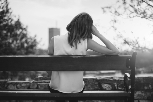 Women looking at the city view from a bench, alone 