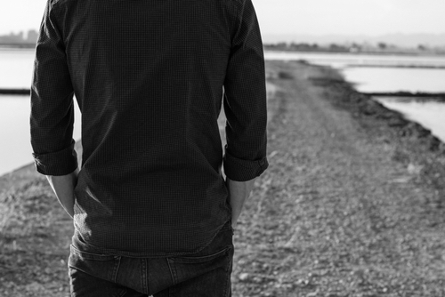 man on his back on a road with his hands in his pocket