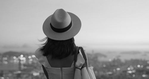 Female, back view, with a hat - watching the city from afar - image of feeling alive, possibilities, emotional freedom.