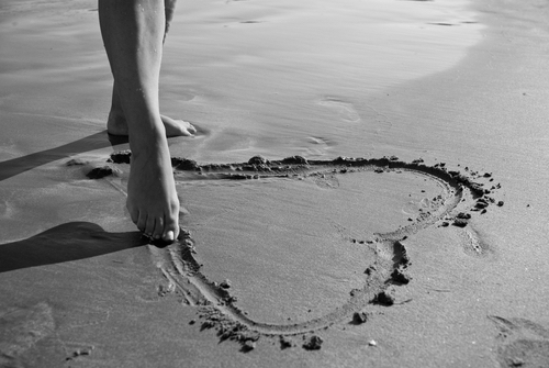 Girl drawing a heart in the sand.