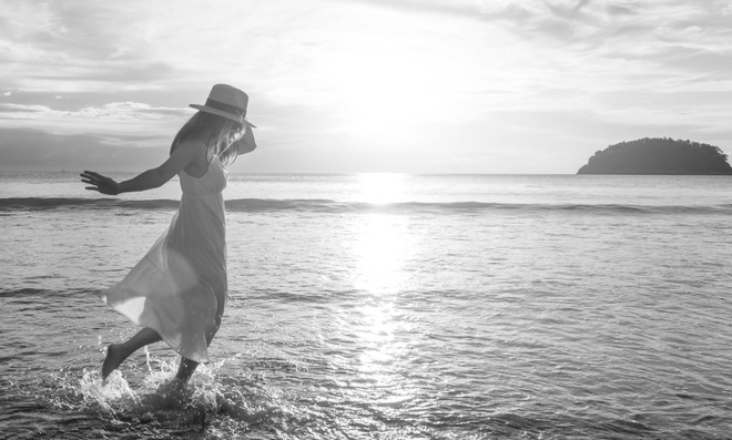 Woman traveler dancing and enjoying beautiful Sunset on the tranquil beach