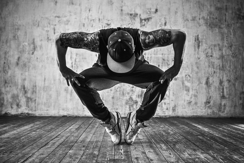 Young man break dancing on wall background. Happy, passionate. Tattoo on body.