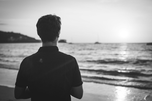 Rear view of a man admiring the sunset on the beach