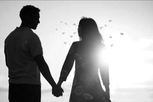 Couple holding hands, looking in the Horizon, at the beach - image of home, togetherness, connection, secure attachment.