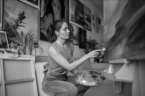 Women painter, alone painting and with her paintings on the wall - not sharing her work.