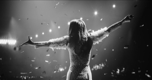 Female singer on stage, back image, hands up, sparkles, and lights, stepping fully into her creativity and performance.