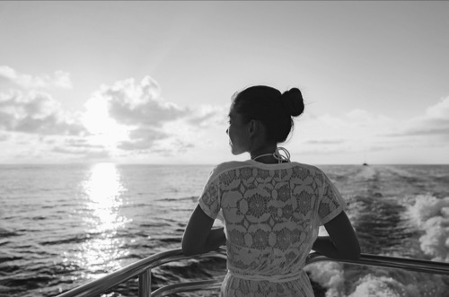 Women on the boat, looking at the horizon - with calm presence, internal reflection, emotional grounding, oppress to the present moment, and strength.