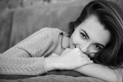 Female portrait, holding her face on her arms, her eyes happy, smiling - image of being happy and content.