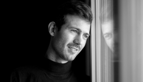 Man smiling at the window, feeling emotionally content