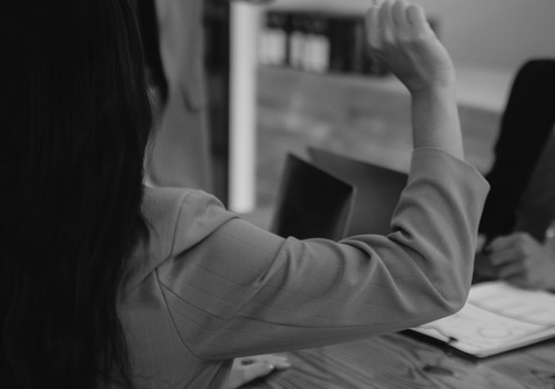 High-functioning female, at work, in charge - raised hand communicating responsibility, engagement, effort. 