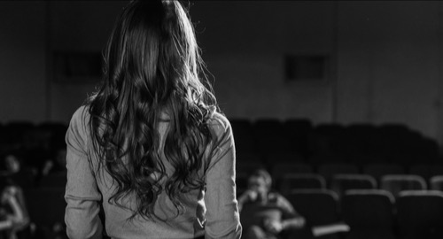 Actress on stage during an audition, back view.