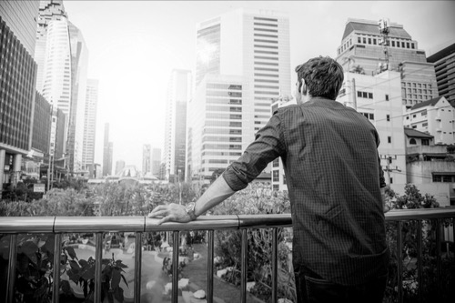 Man, back view, watching the city, form a terrace. Image of healing and hope to be back in the world, participate in creating his life.