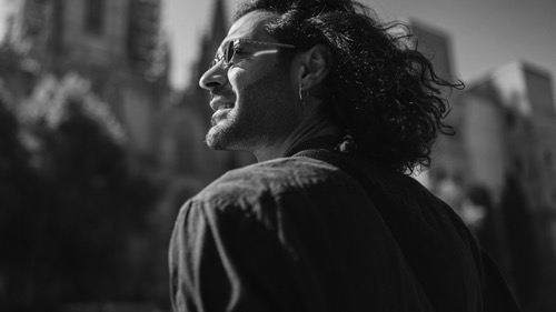 Portrait of man, side view, looking up, smiling, walking in the city. Image of returning back to feeling alive. 